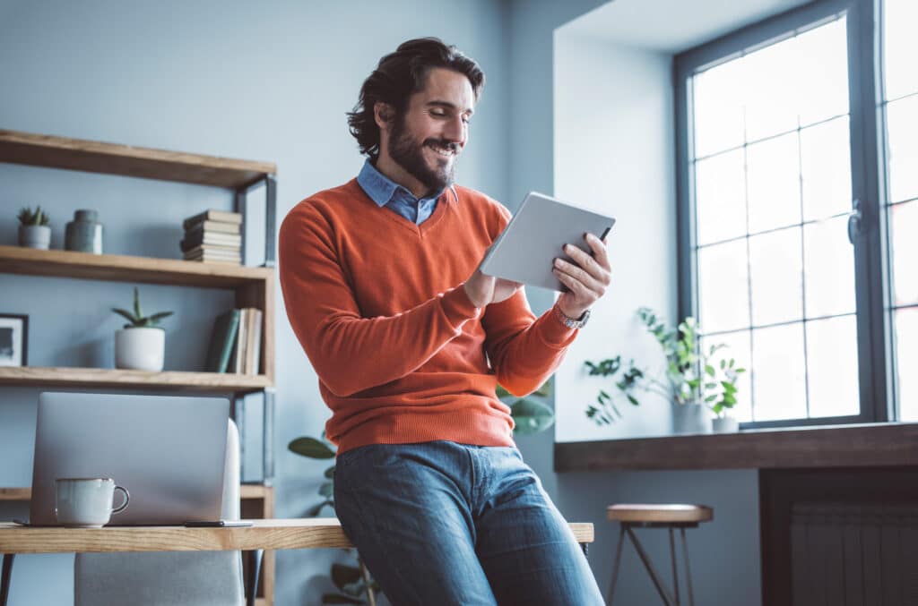 adult male patient paying medical bill on tablet while sitting on a desk